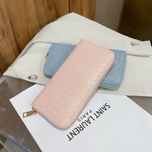 Detail view of women's long crocodile texture wallets in pink and blue with gold zippers