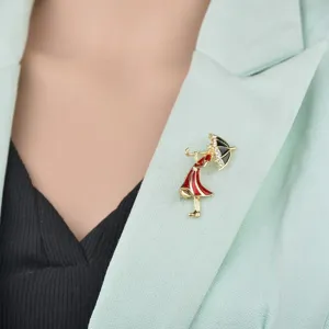 Dettaglio di una spilla smaltata con ragazza e ombrello sul bavero di un blazer verde