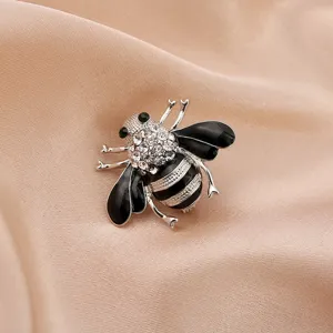 Close-up of a sparkling silver bee brooch with black enamel and clear rhinestones.