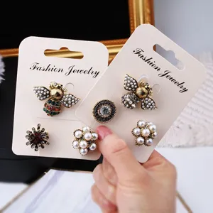 Close-up of elegant vintage baroque bee and pearl rhinestone brooch set on cards