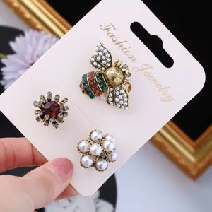 Close-up of vintage Baroque brooch set with pearl bee and rhinestone flower designs.
