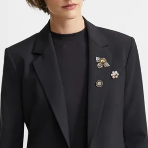 Detailed view of vintage Baroque bee and flower brooch set pinned on a black blazer.