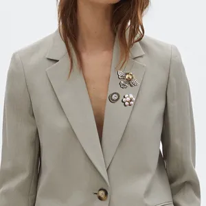 Detailed view of a vintage baroque 3pcs brooch set pinned on a grey blazer lapel