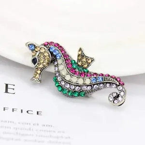 Detailed macro view of a colorful rhinestone seahorse brooch on a white background.