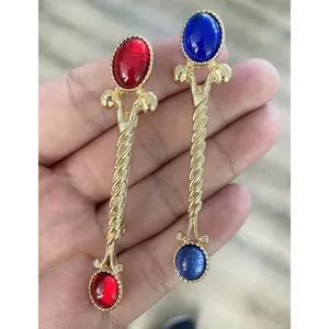 Detail der Vintage-Baguette-Broschen mit roten und blauen Acrylsteinen und Goldfinish.