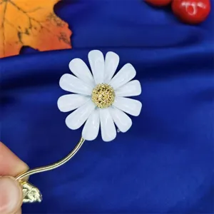 Primo piano dettagliato dei petali in smalto bianco di un'elegante spilla a margherita