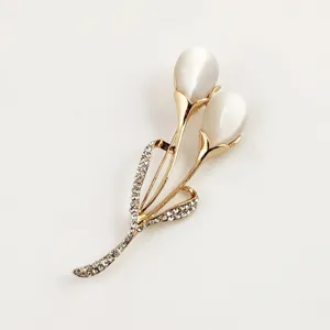 Close-up of white cat's eye stones and rhinestone details on a golden tulip brooch accessory
