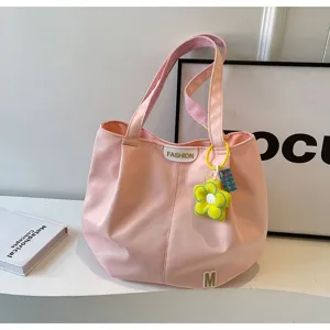 Detalle de bolso tote de lona rosa, con dije de flor amarilla y gran capacidad de carga.