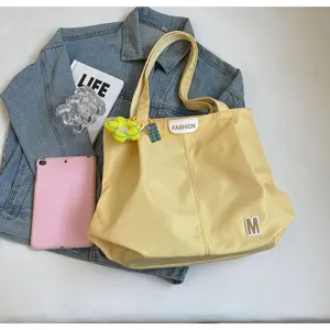 Vista detallada del bolso tote amarillo de lona con parche y bonito colgante de flor.