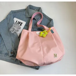 Detalle de bolso tote de lona rosa con colgante de flor y fondo de chaqueta vaquera