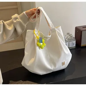 Vista detallada del bolso tote de lona blanca que muestra la correa, el colgante y la textura suave.
