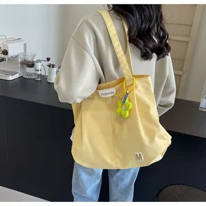 Bolso tote de lona amarillo en detalle, bolso casual para ir a trabajar con colgante de flor.