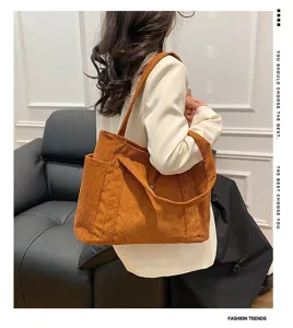 Dettaglio di una grande borsa tote in velluto a coste arancione in uno scatto moda lifestyle.