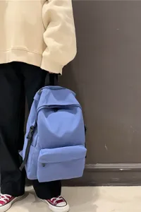 Lifestyle detail of a minimalist solid blue water-repellent nylon backpack for students