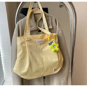 Vista detallada del bolso tote de lona amarilla, bolso de hombro grande con bonito colgante de flor.