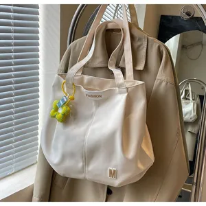 Vista detallada de un bolso tote minimalista de lona blanca con correas para hombro y flor.