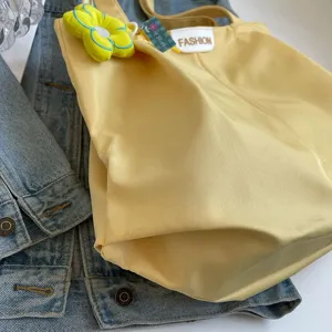 Vista de detalle de bolso tote de lona amarilla, bolso de hombro grande con lindo colgante de flor.
