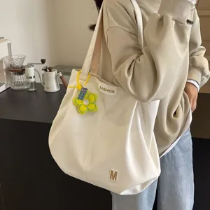 Vista detallada de primer plano del bolso tote de lona blanca con colgante de flor