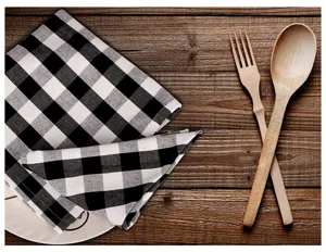 Macro view of black and white checkered cotton napkin on a rustic wooden table.
