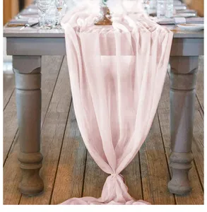 Detailansicht eines rosa Chiffon-Tischläufers auf einem rustikalen Holztisch