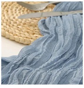 Dettaglio del runner da tavola in garza blu stropicciata con trama morbida