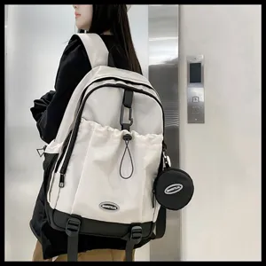 Vue détaillée d'un sac à dos d'école blanc et noir avec poche à cordon sur un modèle.