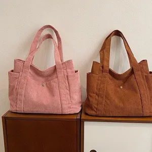 Due grandi borse tote in velluto a coste rosa e marroni su mobile in legno