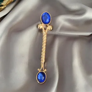 Detaillierte Nahaufnahme einer Vintage Goldenen Brosche mit blauen Steinen auf Seide