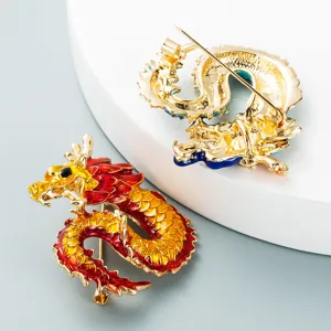 Close-up of enamel zodiac dragon brooches showing intricate gold plating and pin details.
