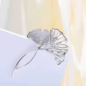 Close-up of silver ginkgo leaf brooch featuring micro-pave zircons and openwork design.