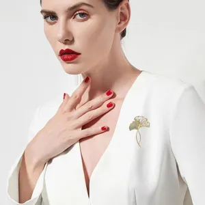 Detail of elegant ginkgo leaf brooch with zirconia on a white suit jacket.