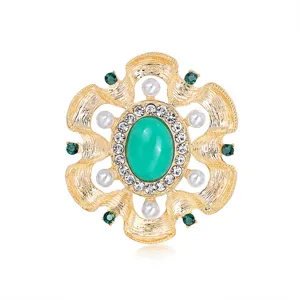 Detailed macro view of vintage baroque brooch featuring a green center stone and pearls