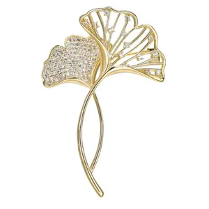 Detailed macro view of elegant golden ginkgo brooch with sparkling micro-paved zircons