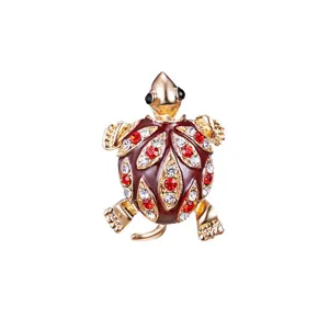 Close-up of retro turtle brooch with red and white rhinestones on golden metal base