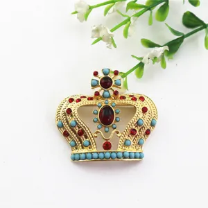 Vista detallada de un broche de corona vintage con piedras rojas y cuentas.