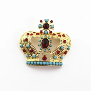 Primer plano detallado de un broche de corona real con piedras rojas y cuentas azules