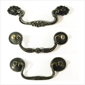 Detailed view of three vintage-style bronze drawer pulls on a white background