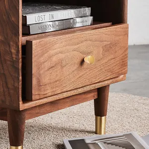 Detalle de un pomo de cajón redondo en oro mate montado sobre un mueble de madera.