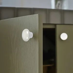 Detailopname van een witte keramische meubelknop voor moderne houten kasten en lades.