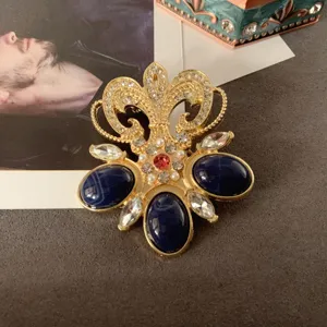Close-up detail of a vintage Baroque gold brooch featuring blue oval stones and sparkling crystals