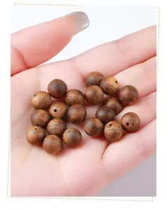 Gedetailleerd overzicht van bruine Agarwood kralen in een hand voor DIY sieraden maken.