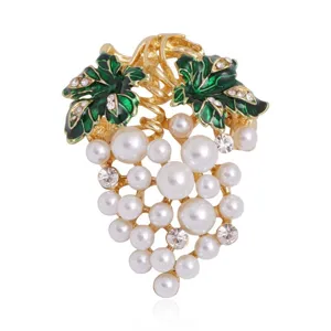 Close-up detail of fashion alloy grape brooch with white pearls and green leaves