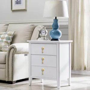 Close-up of elegant gold plastic drop handles on a white three-drawer nightstand.