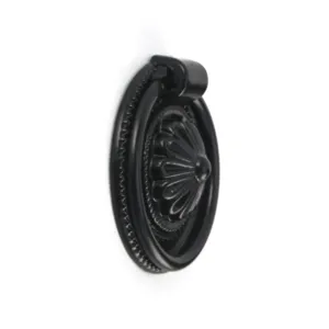 Side view detail of a matte black vintage cabinet pull ring handle with a floral relief pattern