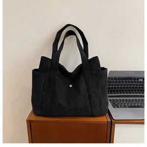 Primo piano di una borsa tote in velluto nero in un ambiente ufficio rilassato.
