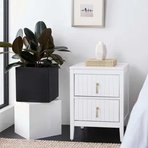 Modern golden pendant drawer handles on a white minimalist nightstand cabinet.