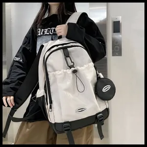 Modèle portant un grand sac à dos blanc à cordon avec accents noirs et pochette