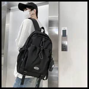 Détail d'un sac à dos noir à grande capacité avec cordon de serrage porté par un étudiant.