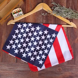 Detail of a pure cotton US flag bandana with star and stripe print draped on a wooden hanger.