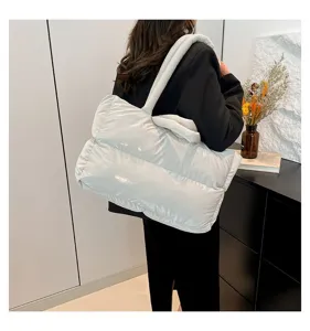 Side view of a white puffer tote bag worn by a model in a minimalist setting.